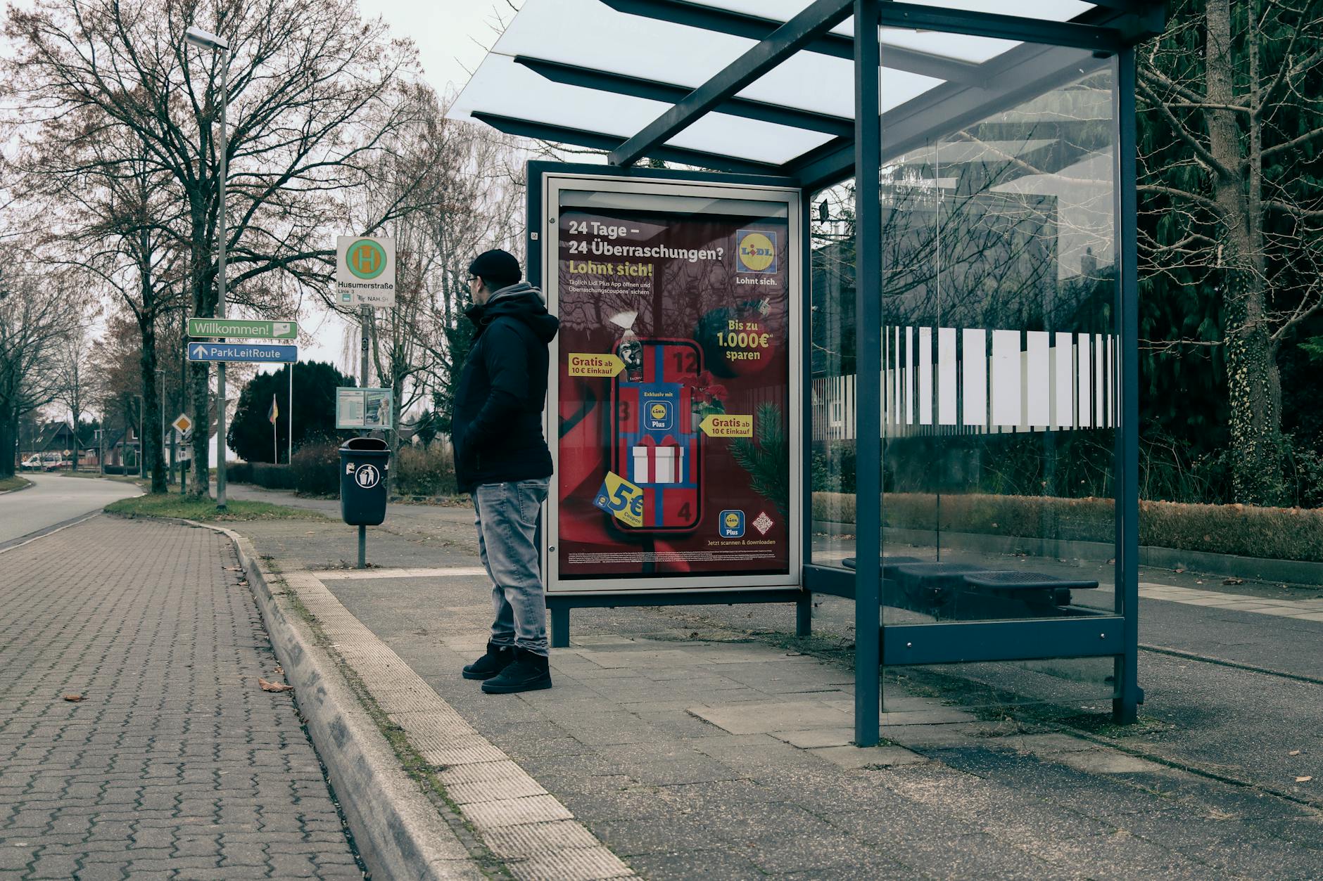 man waiting at a bus stop in winter urban setting